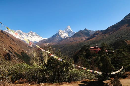 View onto the monastery of the Tengboche village with a prayer flag in the foreground and the peaks of Mount Everest, Lhotse and Ama Dablam in the background, Mount Everest Base Camp Trek, EBC, Nepal 2022