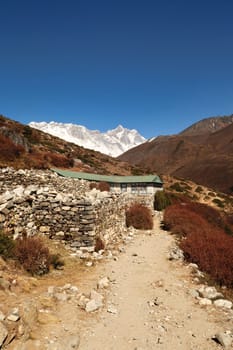 A teahouse surrounded by a stone wall outside of the village of Shomare, Mount Nuptse and Lhotse can be seen in the background, Mount Everst Base Camp Trek, EBC, Nepal 2022