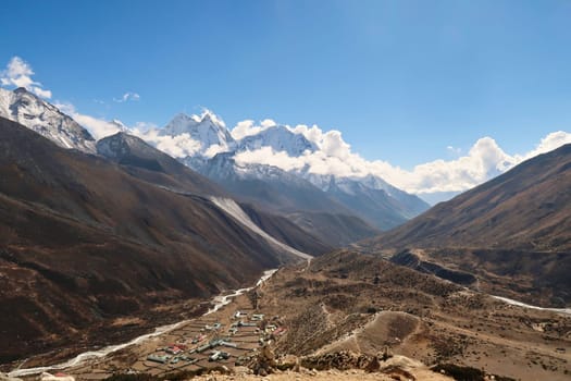 View onto the Dingboche village next to the Imja Khola River, the peaks of Mount Thamserku and Kangtega in the background are partly covered by clouds, Mount Everest Base Camp Trek, EBC, Nepal 2022