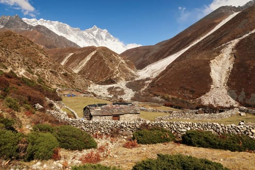 A traditional stone farmhouse with slate roof between Pangboche and Dingboche surrounded by stone walls, Mount Nuptse and Lhotse can be seen in the background, Mount Everest Base Camp Trek, EBC, Nepal 2022