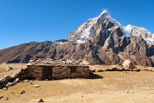 An old traditional stone farmhouse with slate roof in front of Mount Tobuche and Taboche, close to Dingboche, Pheriche village, Mount Everest Base Camp Trek, EBC, Nepal 2022