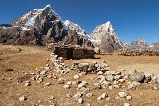 An old traditional stone farmhouse with slate roof in front of Mount Tobuche, Taboche and Cholatse, close to Dingboche, Pheriche village, Mount Everest Base Camp Trek, EBC, Nepal 2022