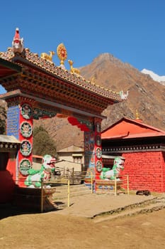 The elaborate colorful entrance gate to the tibetan buddhist monastery of Tengboche, Tangboche village with a dog sleeping right next to it, Mount Everest Base Camp Trek, EBC, Nepal 2022