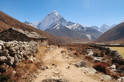 Passing a traditional stone house in the Pheriche valley, Pheriche village in the distance in front of Mount Amphu Gyabjen, Ama Dablam, Kangtega and Thamserku, Mount Everest Base Camp Trek, EBC, Nepal 2022