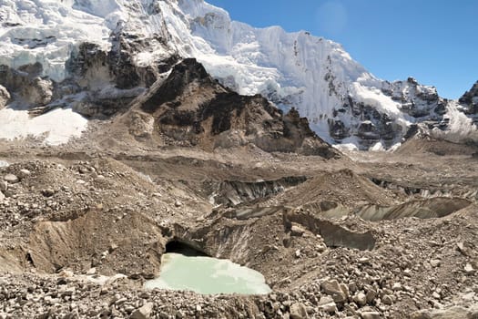 Standing on the Khumbu Glacier, covered by stones, rocks, gravel, green melt water is gathering in little ponds, holes, Mount Everest Base Camp Trek, EBC, Nepal 2022