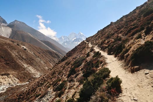 Trail along a steep hill next to Lobuche river between Pheriche and Pangboche village, Mount Kangtega and Thamserku in the background, Mount Everest Base Camp Trek, EBC, Nepal 2022