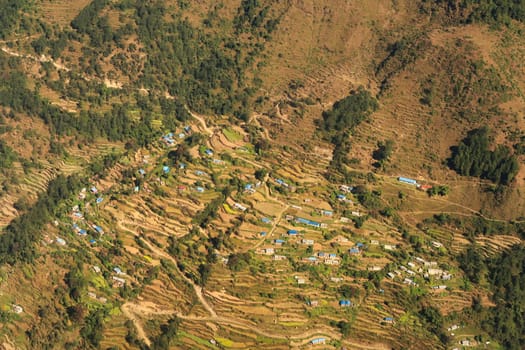 View out of the window on the flight from Lukla back to Kathmandu onto a remote mountain village, traditional houses in between rice terraces, Mount Everest Base Camp Trek, EBc, Nepal 2022