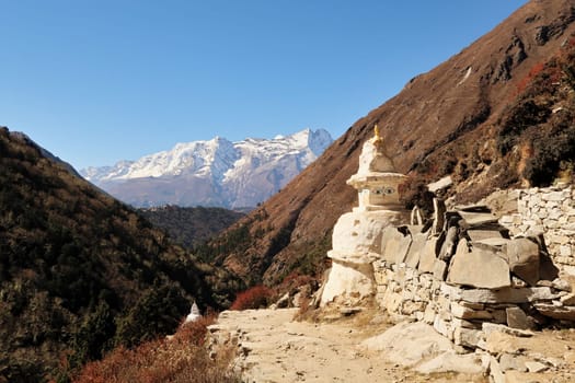 Stupa and Mani stones next to the trail, Tengboche, Tangboche village in front of Kongde Ri peak in the background, Mount Everest Base Camp Trek, EBC, Nepal 2022