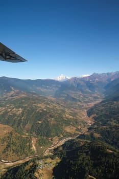 View out of the window on the flight from Lukla back to Kathmandu, villages along a river in front of snow capped peaks of the Himalayas, Mount Everest Base Camp Trek, EBC, Nepal 2022