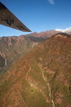 View out of the window on the flight from Lukla back to Kathmandu, the small airplane casts a shadow on a mountain, Mount Everest Base Camp Trek, EBC, Nepal 2022