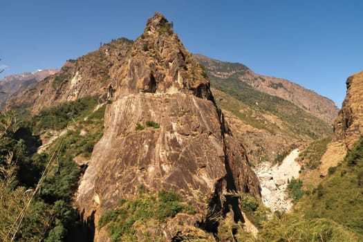 View from the trail onto a giant rock, boulder, that has a part of the road from Besisahar, Bhulbhule to Chame, Manang carved into it, close to Tal village, Annapurna Circuit Trek, Nepal 2022