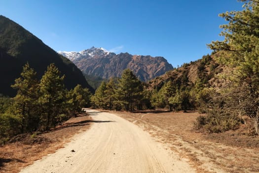 On the trail, road between Dhukur, Dhikur Pokhari and Upper Pisang, the northern ridge of Annapurna II rises in the background, Annapurna Circuit Trek, Nepal 2022