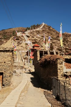 Many stairs are leading up to the Guru Rinpoche Statue and a stupa, pagoda in the traditional mountain village of Ngawal, Annapurna Circuiti Trek, Nepal 2022