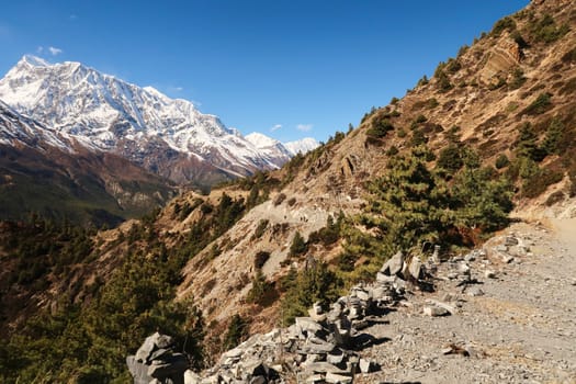On the trail from Upper Pisang, Ghyaru village to Manang, the snow capped peak of Annapurna III is rising in the background, Annapurna Circuit Trek, Nepal 2022