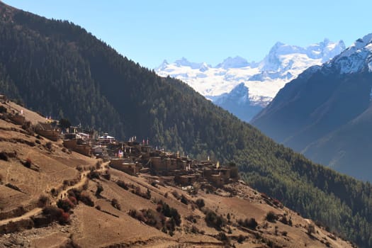 View from the trail to Manang back to the village of Ghyaru in front of the snow capped peak of Mount Lamjung Kailas, Himal, Annapurna Circuit Trek, Nepal 2022
