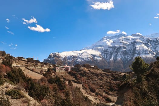 Looking back up to the traditional mountain village of Ngawal, the snow capped peak of Annapurna II is rising in the background, Annapurna Circuit Trek, Nepal 2022