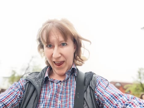 A mature female traveler captures a joyful selfie while exploring a scenic location on her latest excursion.