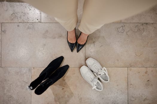 Shoes fitting concept. Shot with view from above on female feet wearing new fashion high-heels and two pairs of different footwear