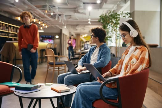 Young workers working online in modern comfortable office. Some teenagers with laptops at workplace