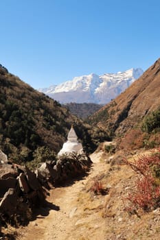 Stupa and many stacked Mani stones next to the trail, Tengboche, Tangboche village in front of Kongde Ri peak in the background, Mount Everest Base Camp Trek, EBC, Nepal 2022