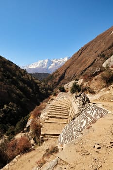 Tibetan buddhist Mani stones next the trail, stairs, Tengboche, Tangboche village in front of Kongde Ri peak in the background, Mount Everest Base Camp Trek, EBC, Nepal 2022