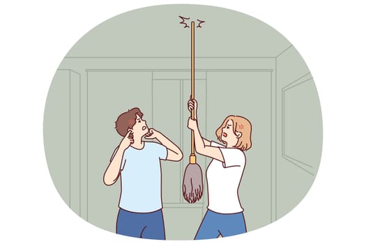 Young couple bangs on ceiling with mop urging neighbors to stop party or turn off loud music. Angry men and women use mop suffer from noisy neighbors not respecting rules of living together
