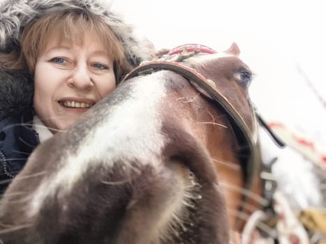 Smiling woman takes a selfie with a horse while exploring a new destination on her travel journey.