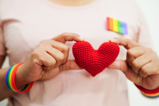 Asian woman holding red heart with rainbow flag, LGBT symbol rights and gender equality, LGBT Pride Month in June.
