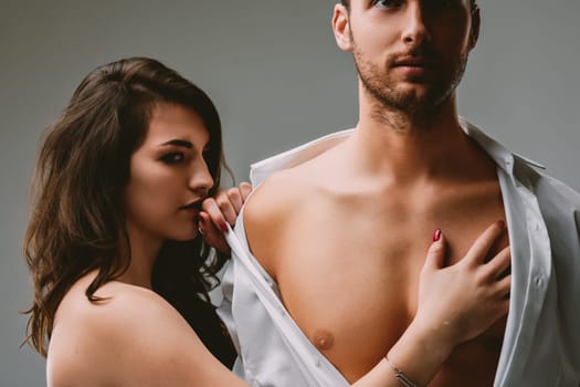 Woman with dark hair and red nails touches a man's chest, smiling seductively. He tries to appear indifferent, but his eyes betray his strong desire for her