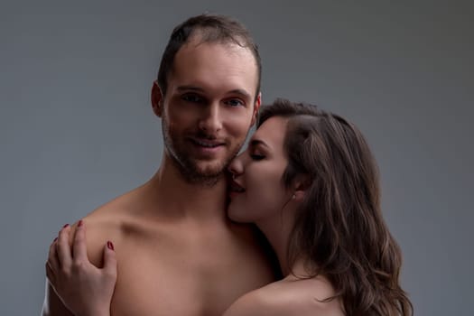 dark-haired woman, showing intense desire, embraces a shirtless man. He smiles, almost in ecstasy, anticipating what is to come, feeling deeply desired and cherished by her