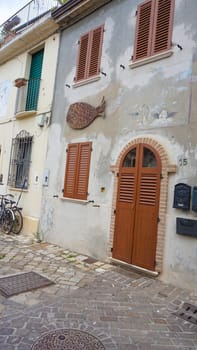 Rimini, Italy - June 25, 2024: Art installation on wall at Borgo San Giuliano typical street with low and colorful houses at Rimini, Italy