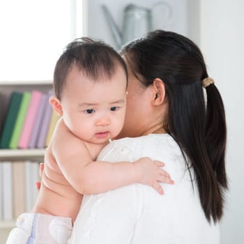 Asian mother pampering six months old baby girl at home.