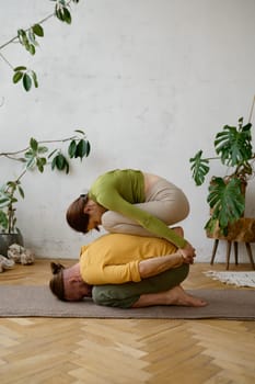 Active young couple resting in child pose while practicing yoga together at home. Family workout