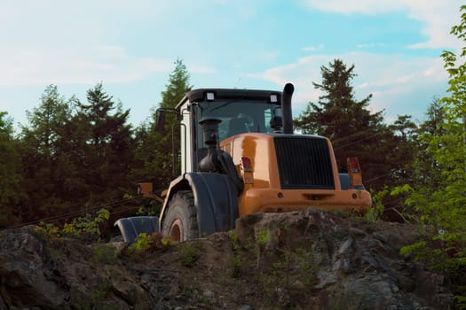 Heavy-duty yellow backhoe excavator in action at a construction site, carrying out earthmoving activities using hydraulic machinery