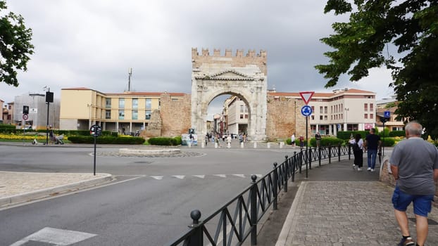 Rimini, Italy - June 25, 2024: People are passing Arch of Augustus, triumphal ancient architecture of Roman Empire, 27 BC at Italy