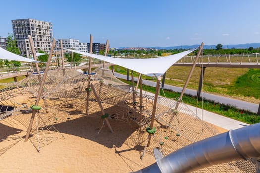 Large public city playground with slides and climbing frame, panorama of modern urban area