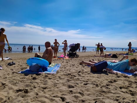 Rimini, Italy - June 25, 2024: People going along Rimini beach. The sunbeds and parasols on the beach