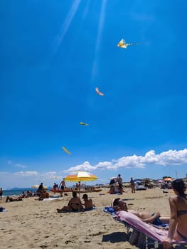 Rimini, Italy - June 25, 2024: People going along Rimini beach. The sunbeds and parasols on the beach
