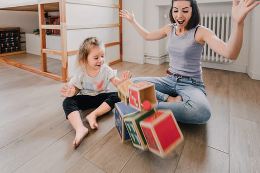 Mother and daughter play with colorful wooden cubes, bonding and creating joyful memories in their living room