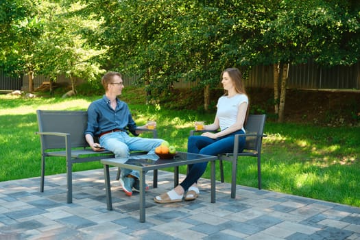 Father and daughter relaxing outdoor in a lush backyard, speaking and sharing their news
