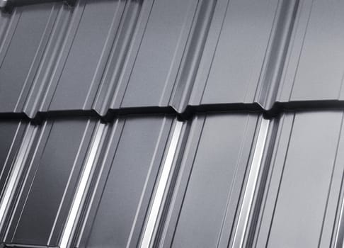 Close-up view modular tile effect roof panel. Lightweight galvanised steel roofing sheet. Traditional metal shingle tiles. Popular profiled metallic pantile mimic clay or concrete slate