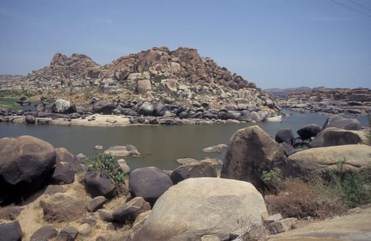the Landscape and River with the typical Stones and Hills round of the town of Hampi in the Province of Karnataka in India.  India, Karnataka, March, 1998