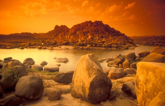 the Landscape and River with the typical Stones and Hills round of the town of Hampi in the Province of Karnataka in India.  India, Karnataka, March, 1998