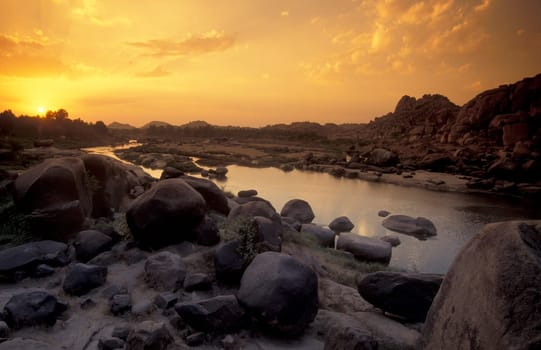 the Landscape and River with the typical Stones and Hills round of the town of Hampi in the Province of Karnataka in India.  India, Karnataka, March, 1998