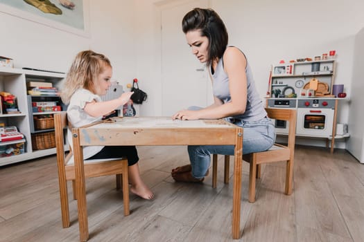 Mother and daughter happily playing with toys in a bright playroom, bonding and creating together in a cozy space filled with love and laughter