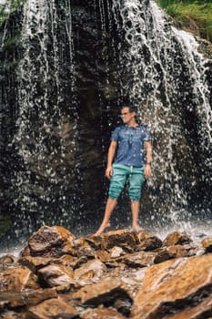 Man at waterfall in summer Altai Mountains. Blurred background