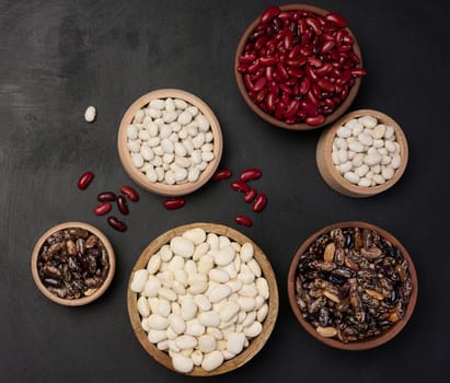 Raw white and red beans in a plate on a black table, top view. Assortment