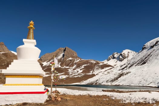 A buddhist stupa, pagoda in front of the Ice Lake, Kicho Tal, Khicho Ice Lake on a sunny day, close to Manang, Annapurna Circuit Trek, Nepal 2022
