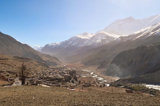 View from the trail back to the village of Gunsang, the town of Manang and the Marsyangdi River, the wind stirs up a lot of dust over the valley, Annapurna Circuit Trek, Nepal 2022