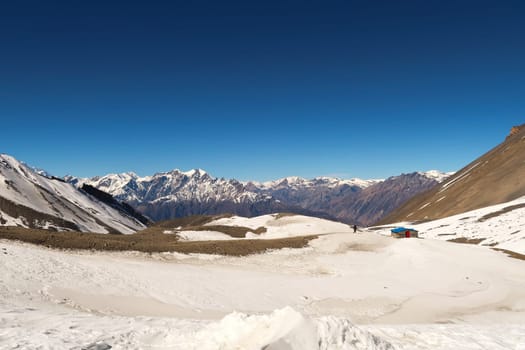 The trail down from Thorong La, Thorung La, Thorang La pass to Muktinath running through a snow covered landscape in front of a mountain range, Annapurna Circuit Trek, Nepal 2022
